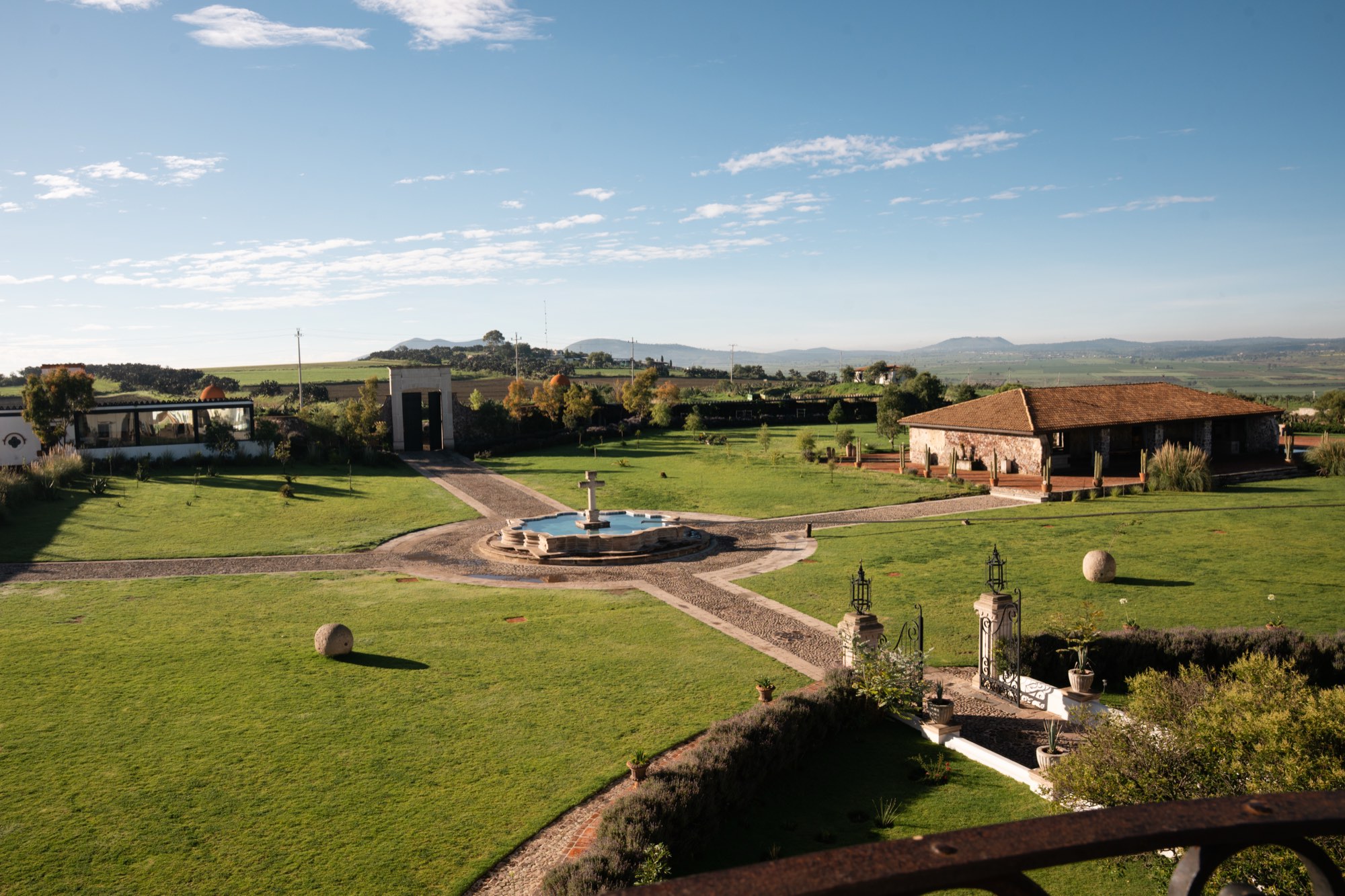 Vista de los jardines y la fuente de la hacienda con la sierra al fondo